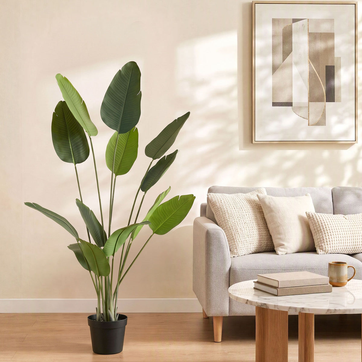 Artificial bird of paradise plant with green textured leaves in a black pot