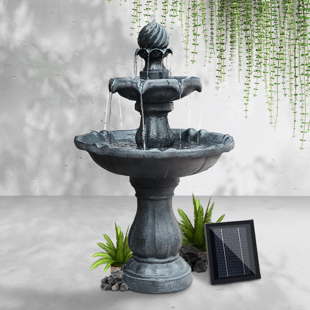 Dark gray solar bird bath fountain with panel on ground, water flowing from spout