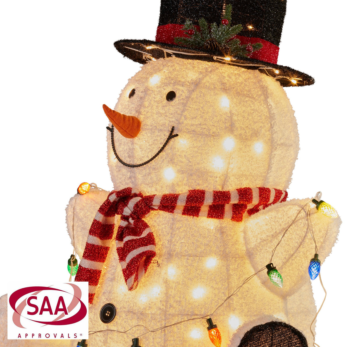 Close-up sitting snowman with black top hat, orange nose, red striped scarf, LED lights