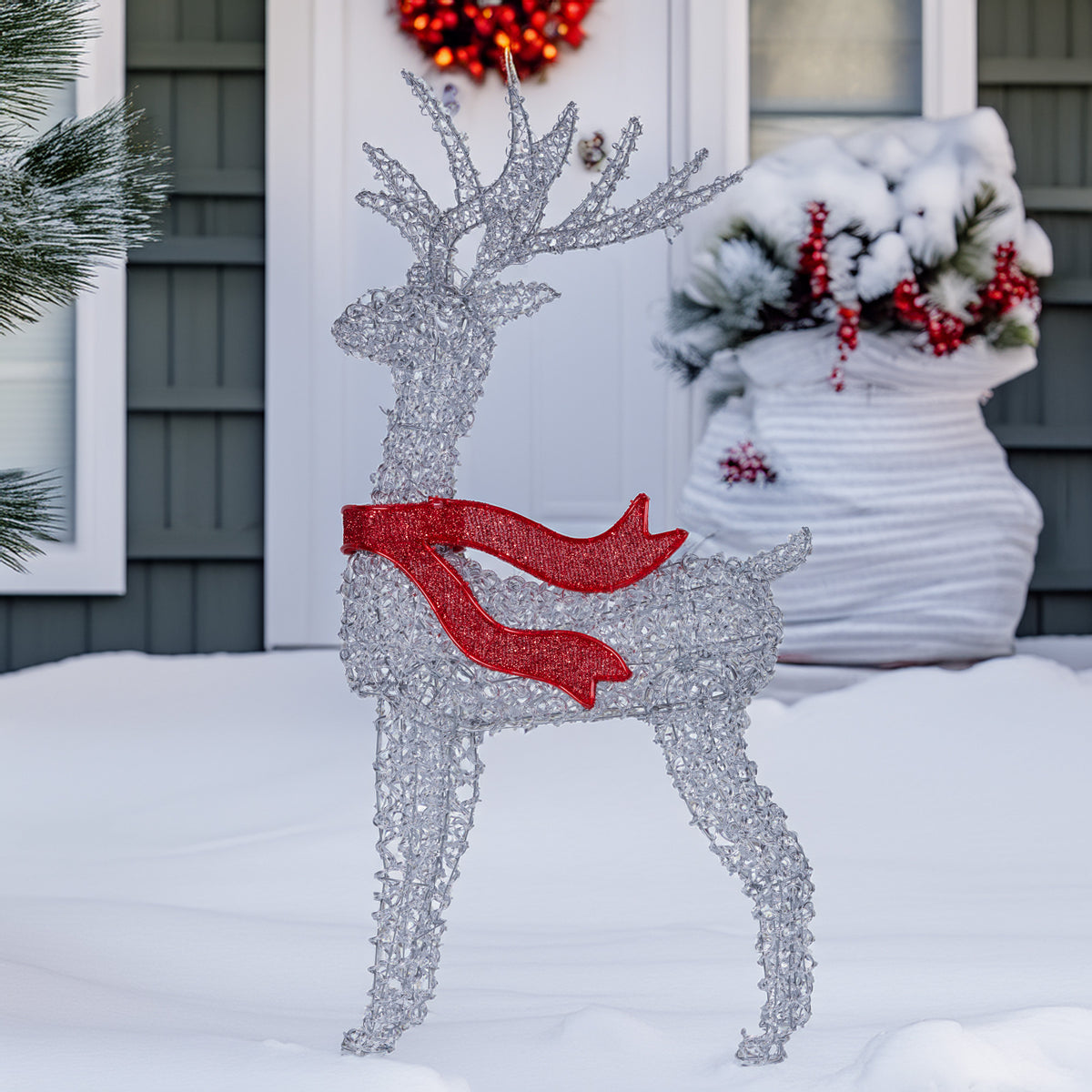 Light-up reindeer outdoor decoration with red bow accents, standing on snow