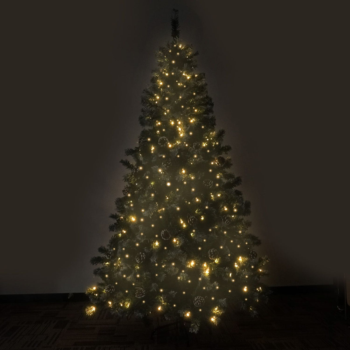 Tall artificial Christmas tree lit with warm yellow LED lights