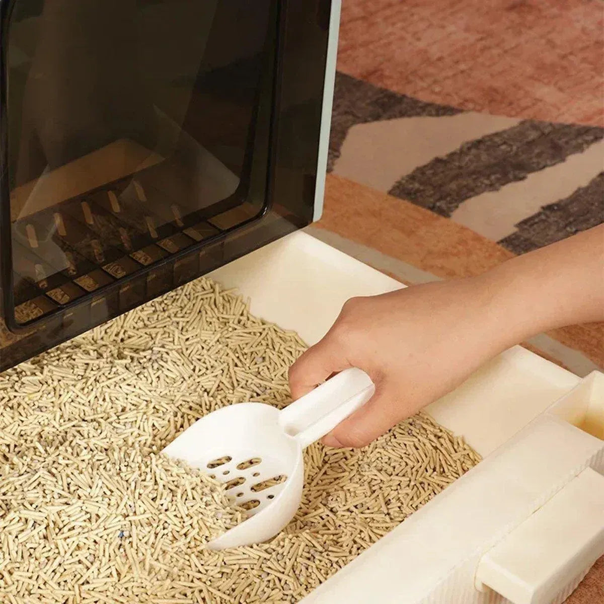 Open drawer of enclosed cat litter box with litter scoop on floor