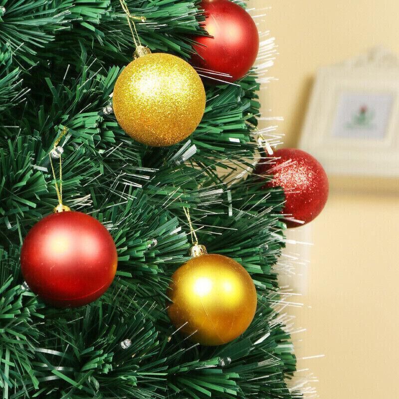 Gold, red, and glitter bauble ornaments on a green artificial Christmas tree branch