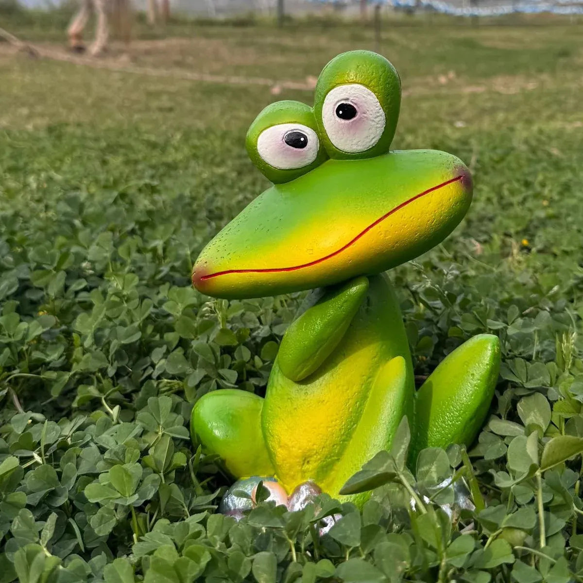 Green frog garden ornament statue crouching in grass, bulging eyes, flower base