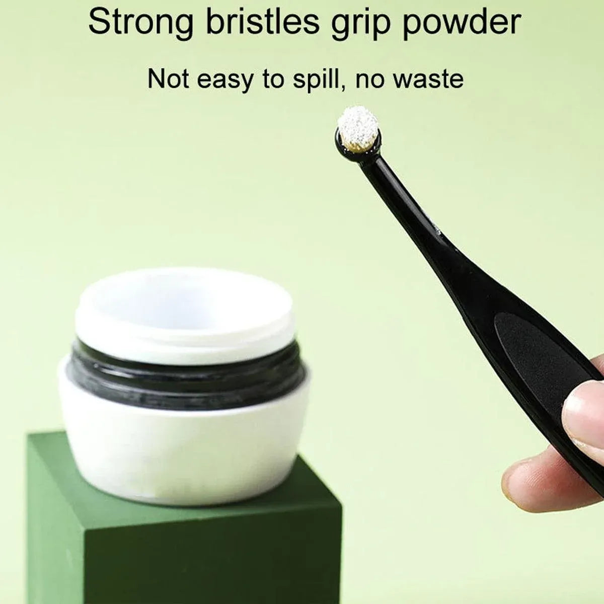 Black pet stain remover brush with orange bristles near white powder container