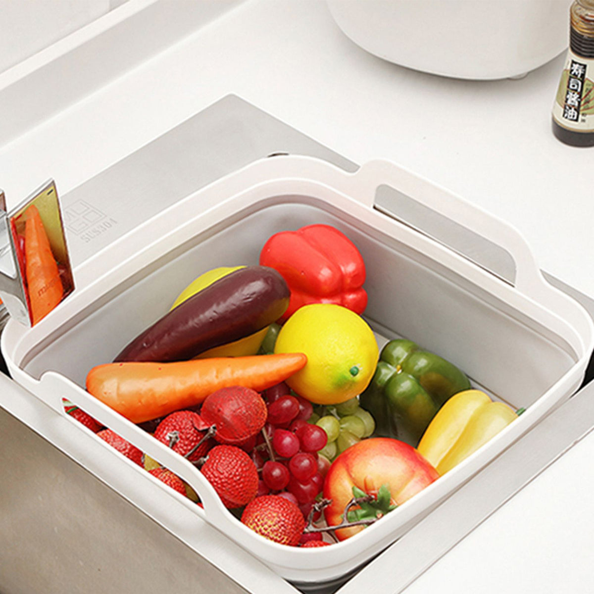 Grey and white collapsible strainer basket filled with mixed fresh produce for washing