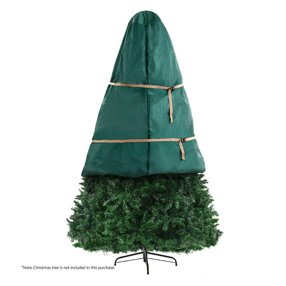 Green Christmas tree storage bag with tan straps, holding an artificial tree