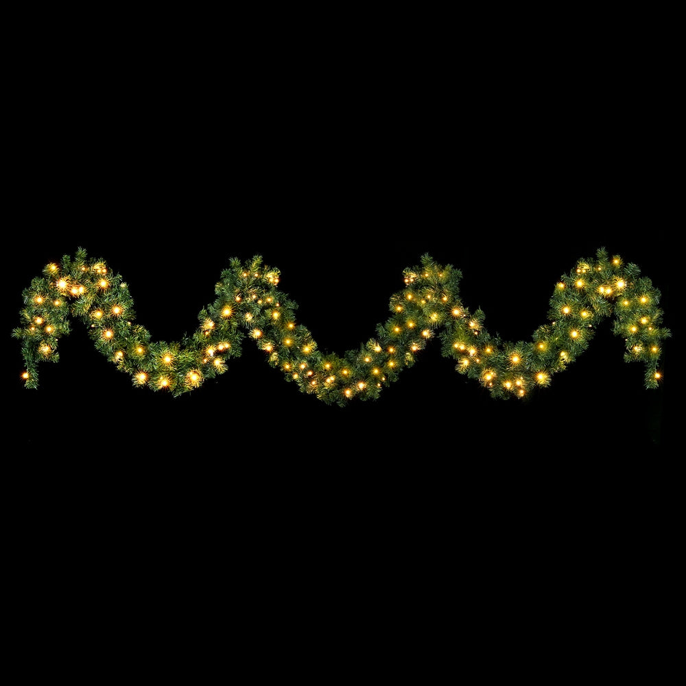Pre-lit green Christmas garland with warm white LED lights along wavy tips