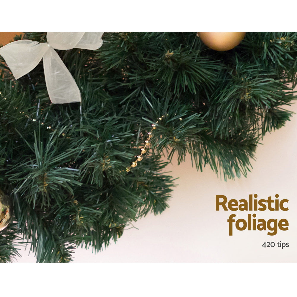 Close-up of a Christmas wreath with realistic foliage and decorative elements on a white background.