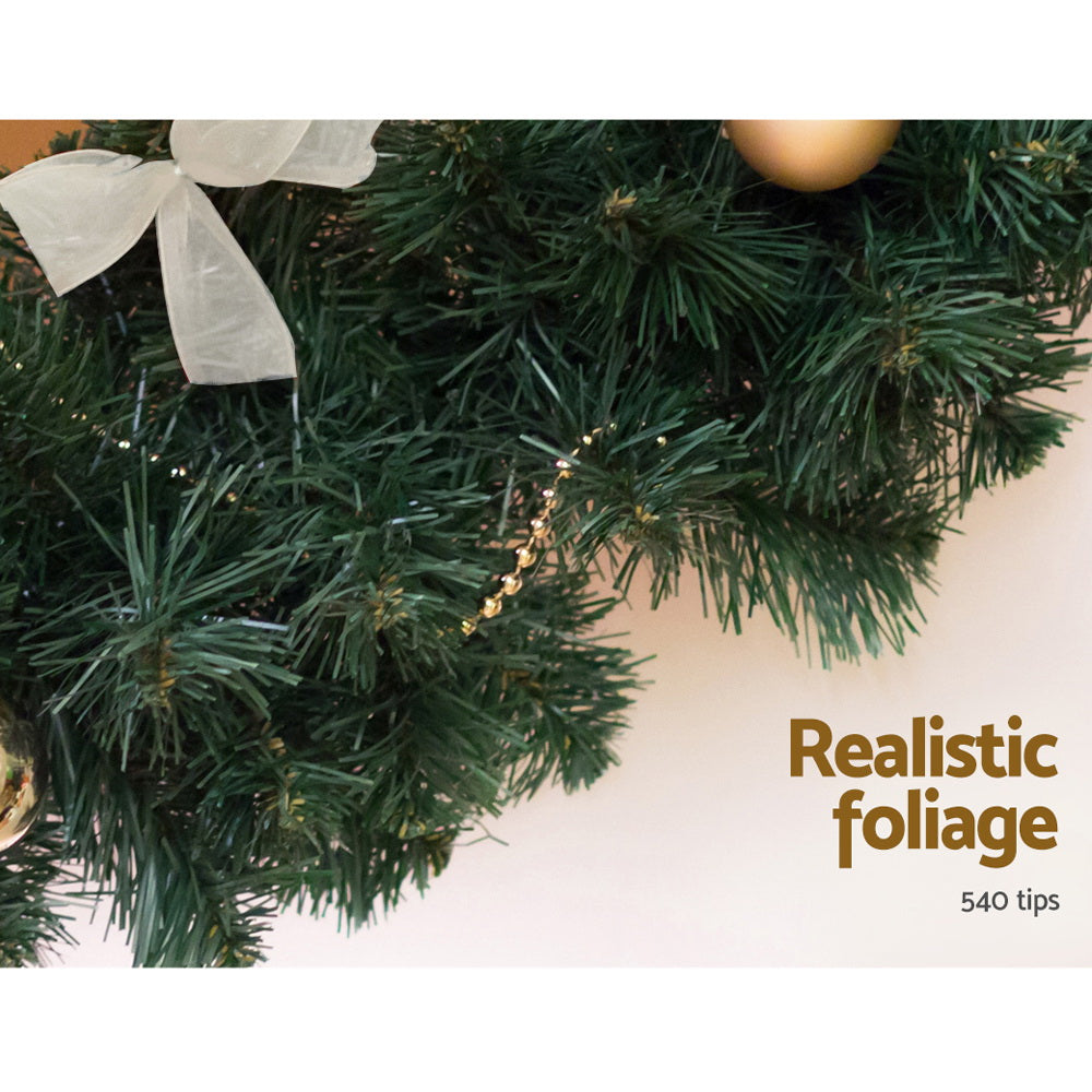 Green garland branch with pine tips, small warm lights, and a white accent bow