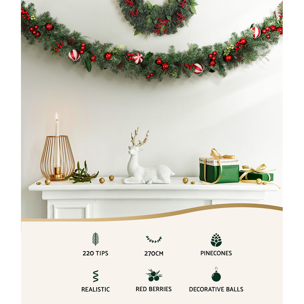 Christmas garland with dark green foliage, red berries, and striped candy-cane baubles