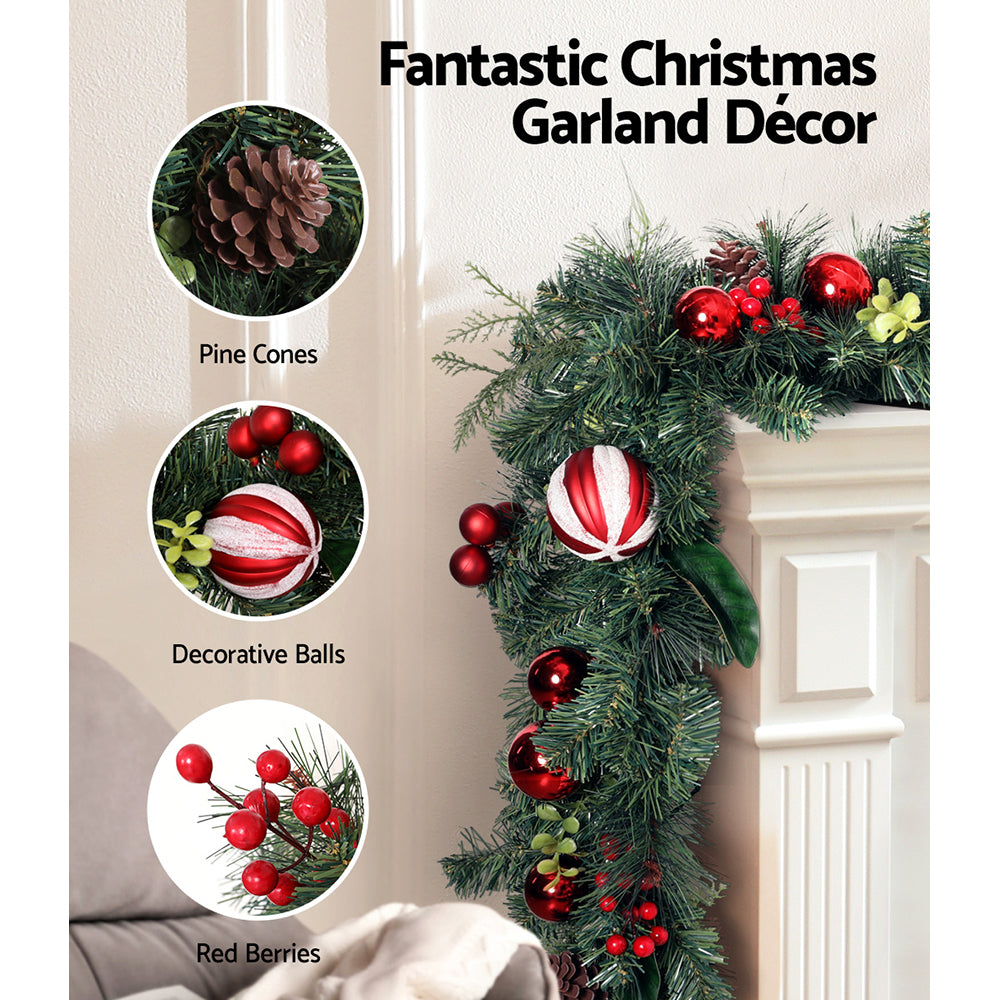 Christmas garland decor with dark green pine, red glossy balls, and white-red striped ornaments