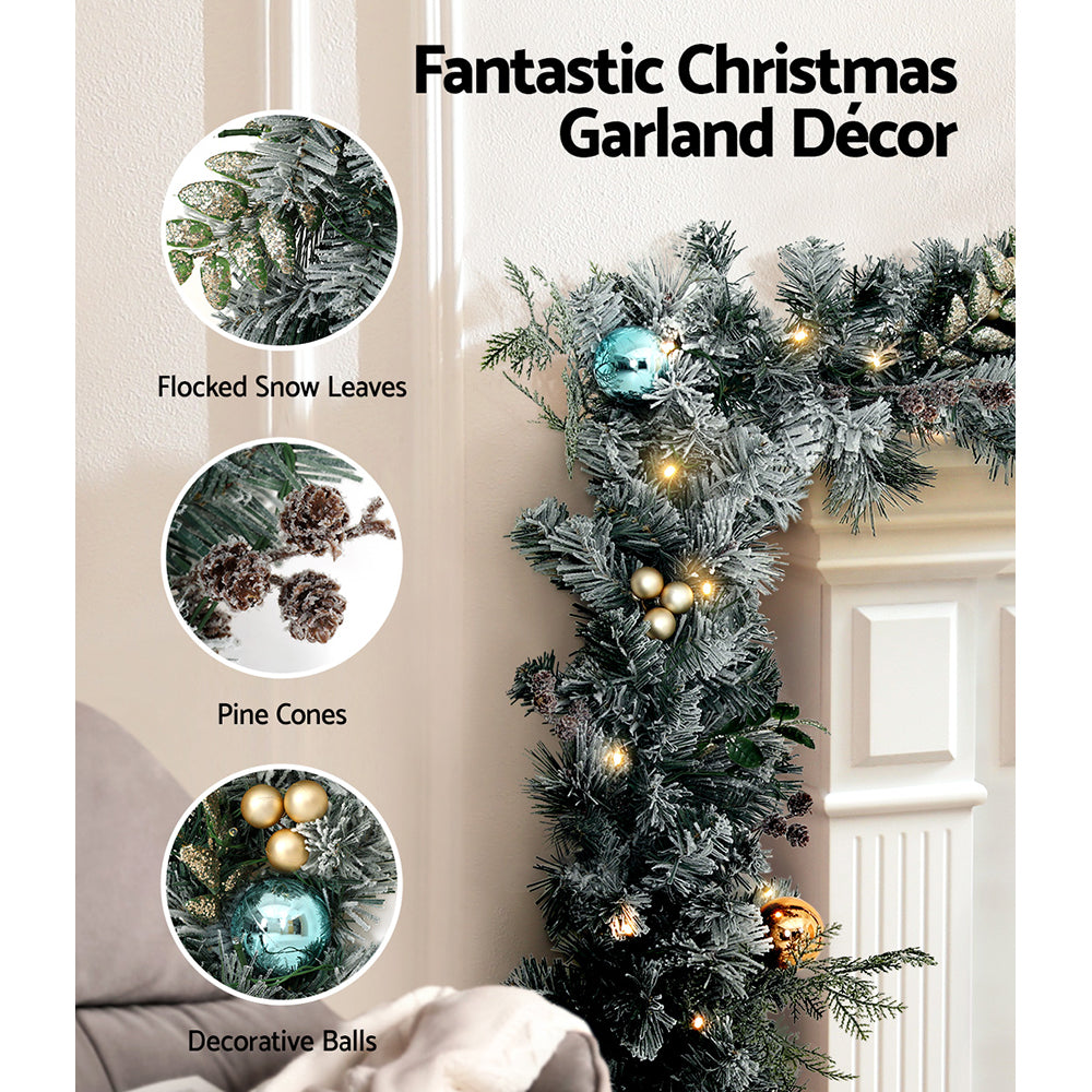 Flocked Christmas wreath decor with LED lights and gold, teal, and bronze bauble ornaments