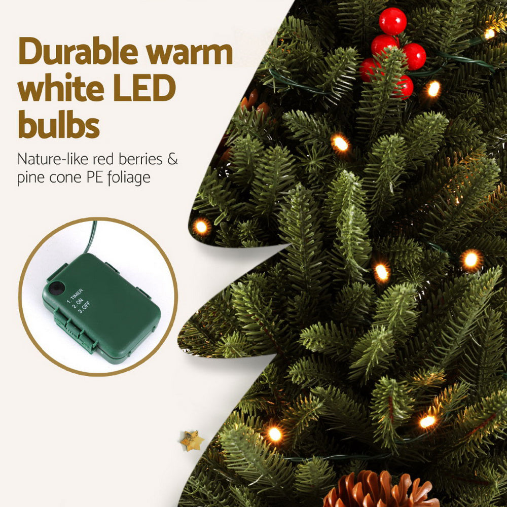 Artificial Christmas tree branch detail with warm white LED bulbs and red ornaments