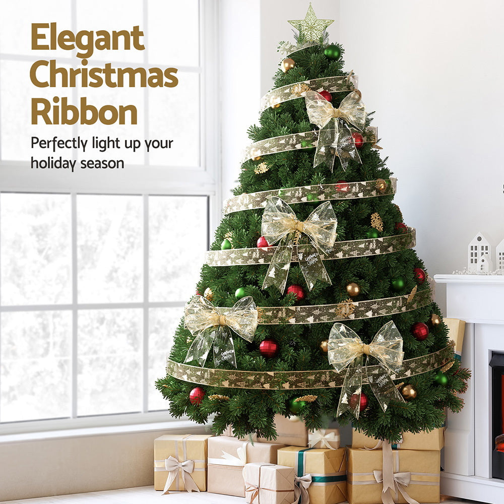 Christmas tree decorated with white-and-gold printed ribbon bows and ribbon streamers.