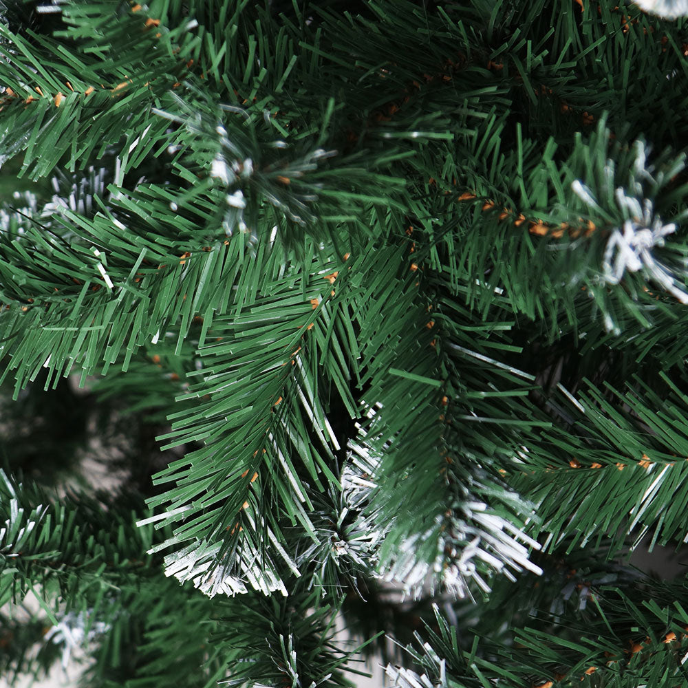 Close-up of a green artificial Christmas tree branch with snow-like texture.