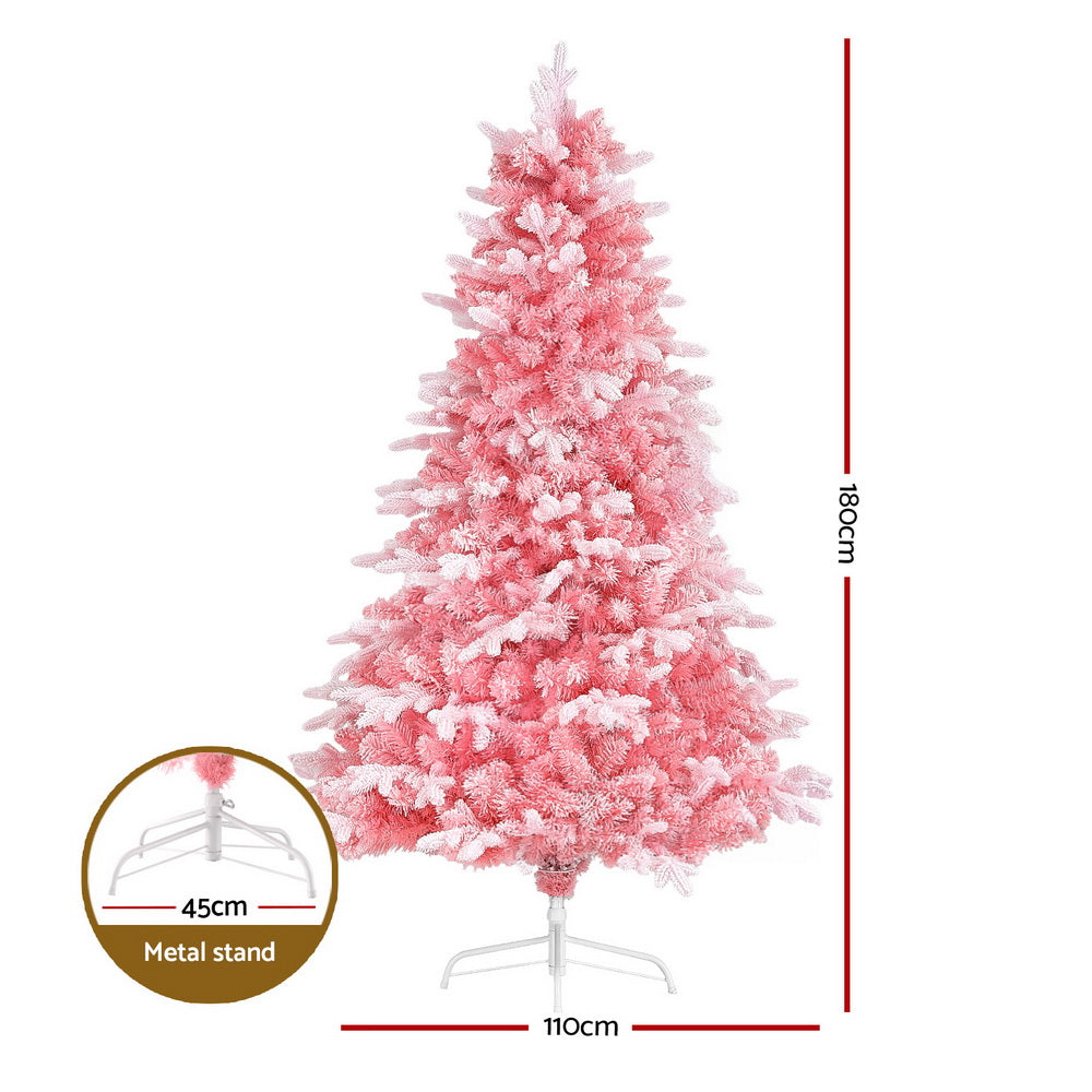 Pink snowy artificial Christmas tree standing on a metal support base