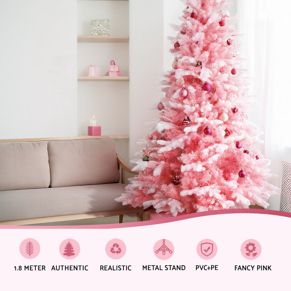 Pink snowy artificial Christmas tree with snow-dusted tips and ornaments