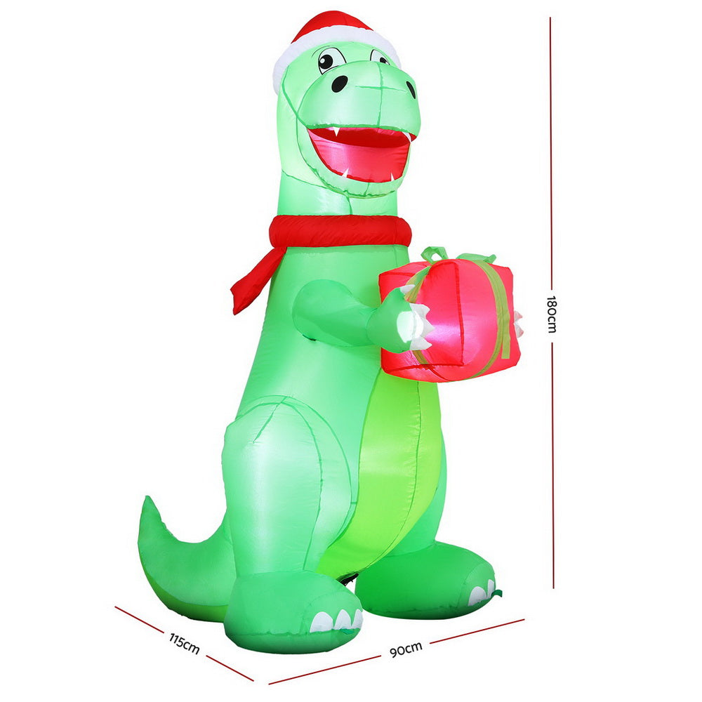 Inflatable green dinosaur in Santa hat holding a pink gift box, red scarf, LED lights