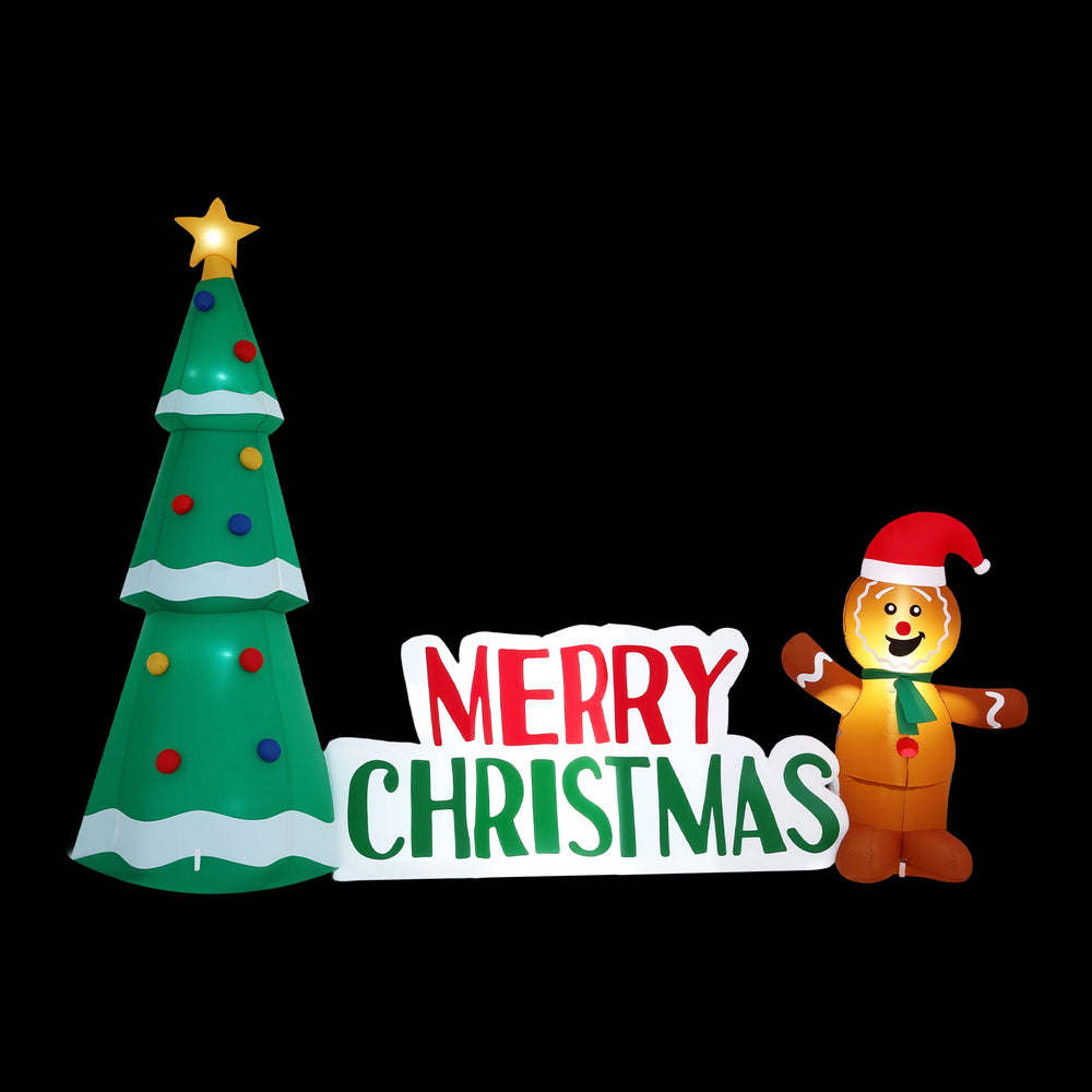 Inflatable Christmas tree with LED sparkle and Merry Christmas sign beside gingerbread figure