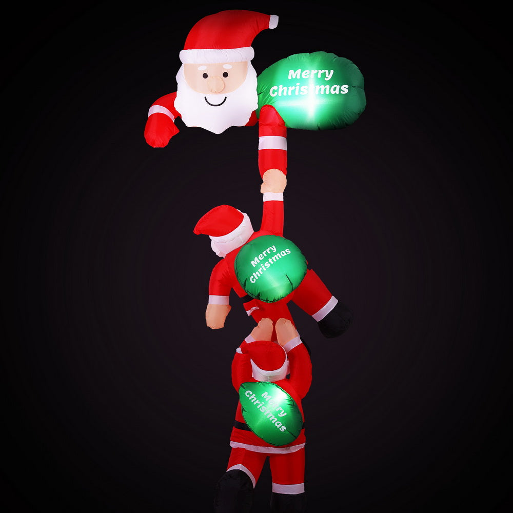 Climbing Santa inflatable with green glowing “Merry Christmas” balloons
