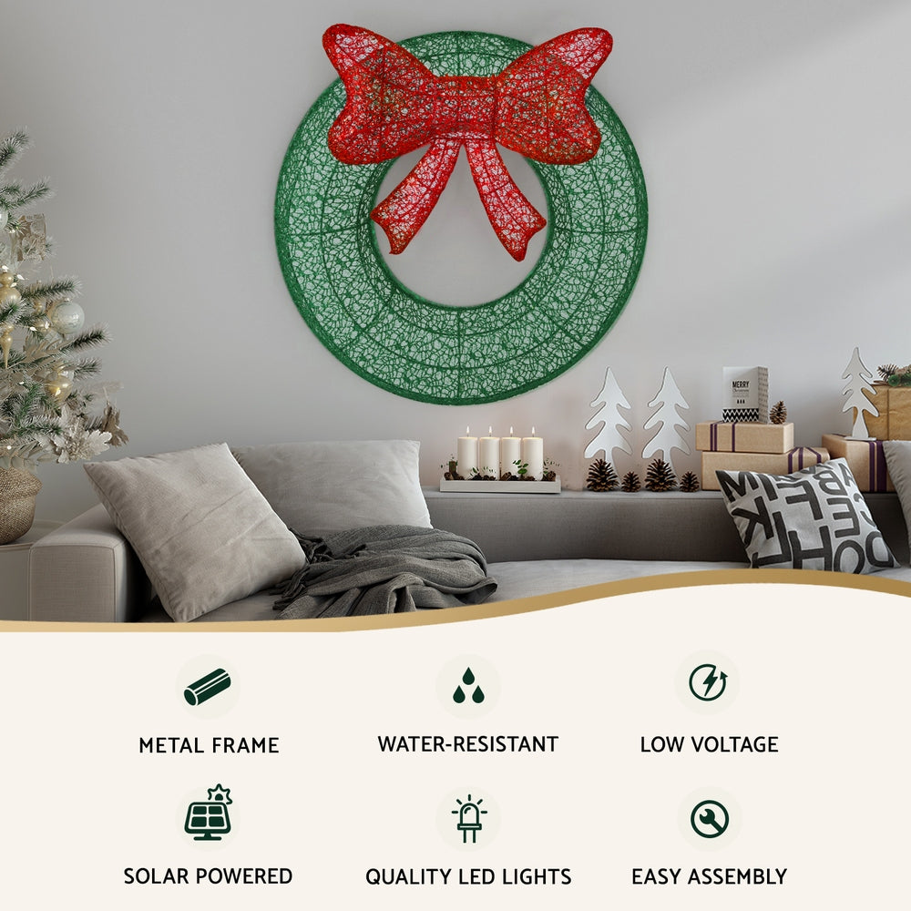 Lighted Christmas wreath decoration with red glitter bow on green mesh ring