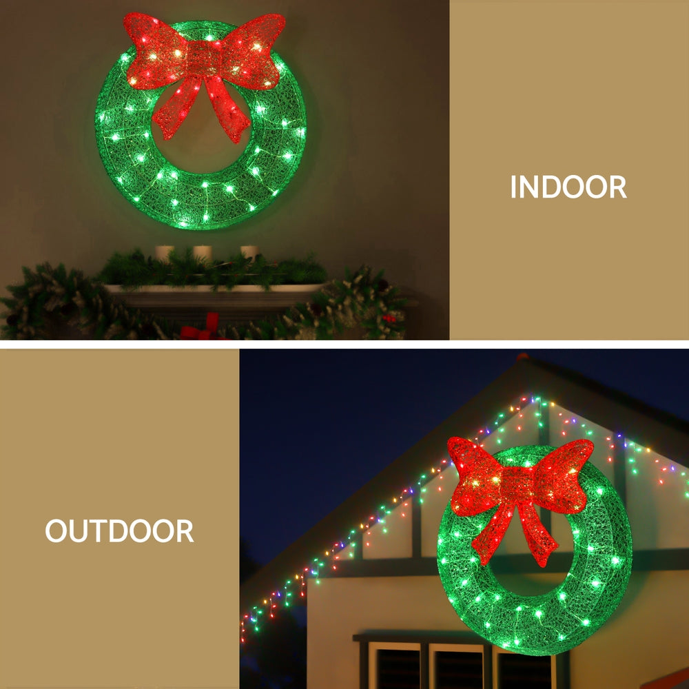 Lit Christmas wreath with red bow and green frame, glowing green LED lights