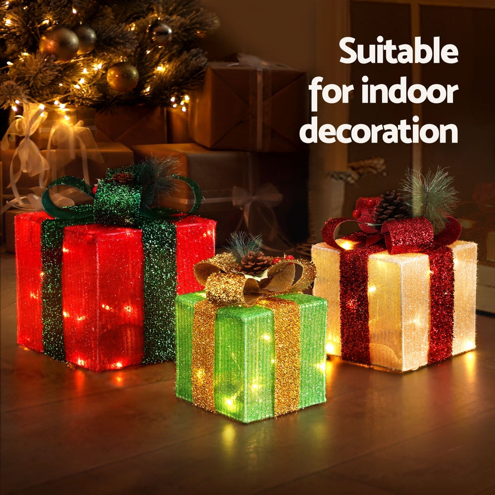 Three Christmas gift box lights showing warm white glowing LEDs on fabric boxes