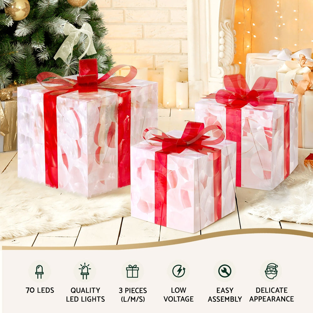 Illuminated clear gift boxes with red bows for Christmas decor on a floor