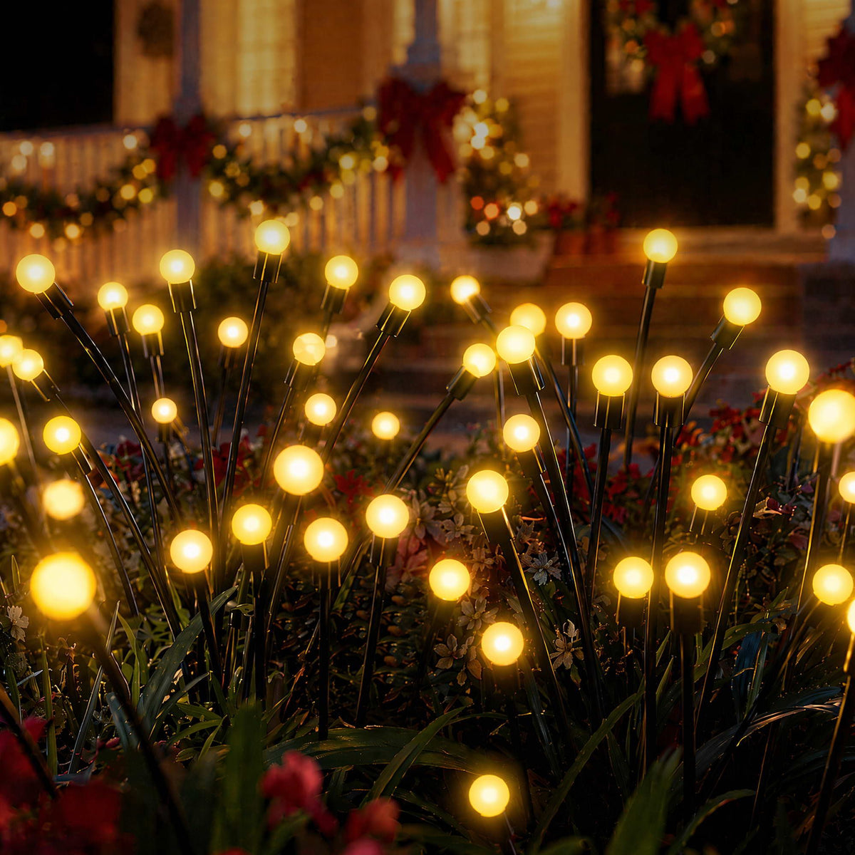 Warm white solar firefly stake lights glowing among garden plants at night